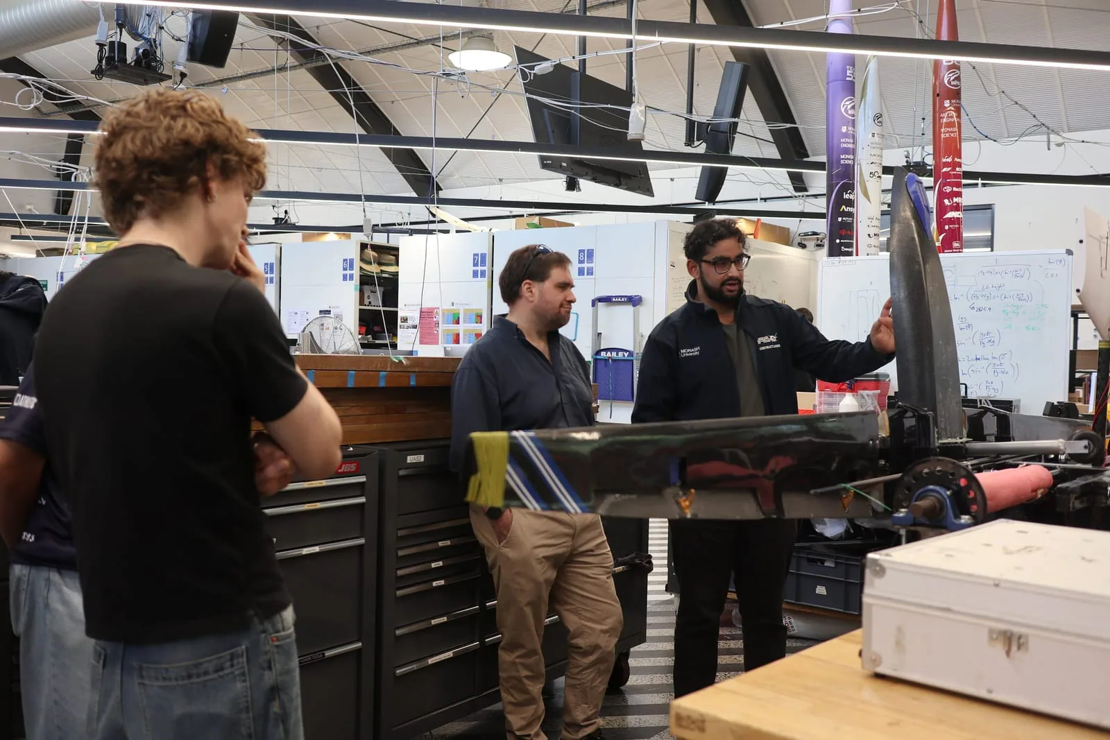 MUAS students and industry visitors discussing an uncrewed aircraft in the workshop